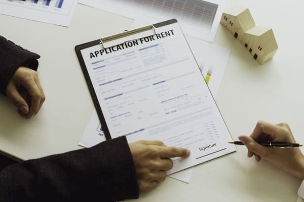 A real estate professional pointing at a rental application and a tenant signing