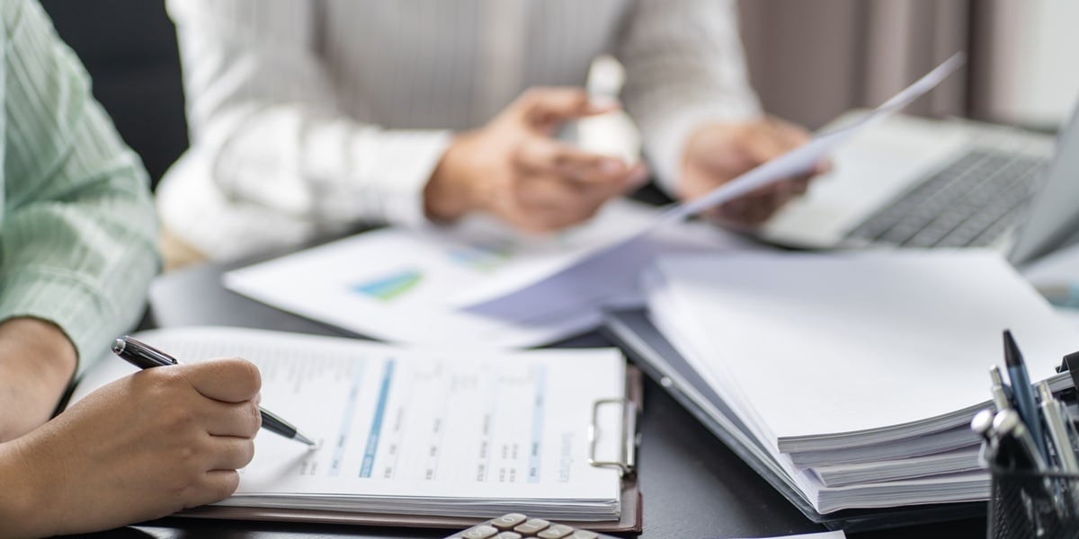 Two people looking at sheets and a calculator